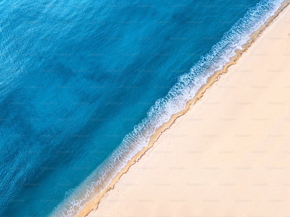 Aerial view of an idyllic sea sandy beach with an incoming azure wave. The concept of holidays in tropical countries and relaxation. Background for travel and vacation