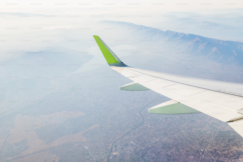 Airplane wing over distant autumn mountains