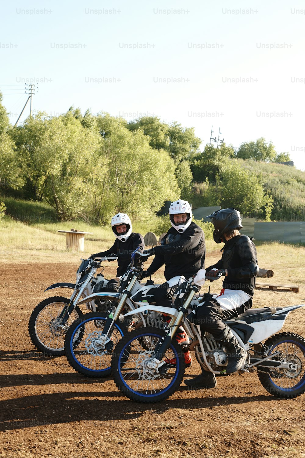Grupo de motociclistas sentados em motocicletas e conversando uns com os outros antes da competição off-road