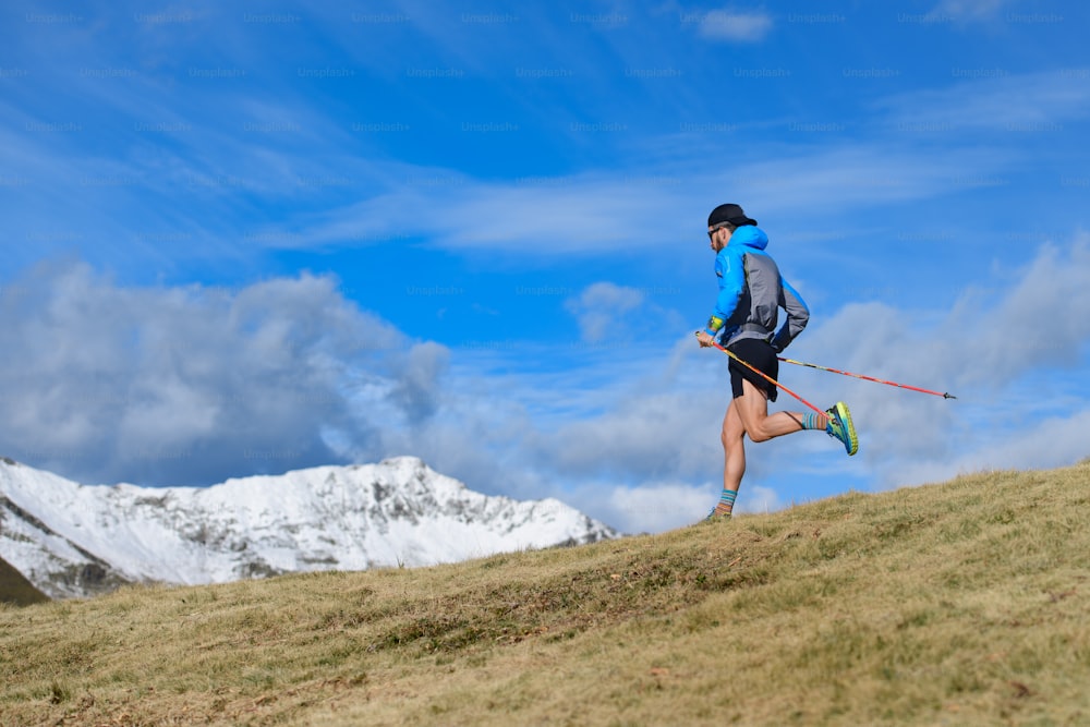 Ein Mann trainiert für Ultra-Laufstrecke in den Bergen im Herbst mit dem ersten Schnee auf den Bergen