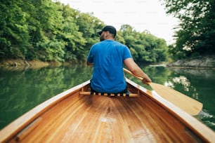 Rear view of man paddling canoe in the lake forest.