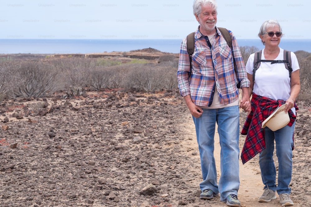 Retrato de um belo casal de viajantes idosos em excursão ao ar livre em paisagem árida.  Horizonte sobre o mar