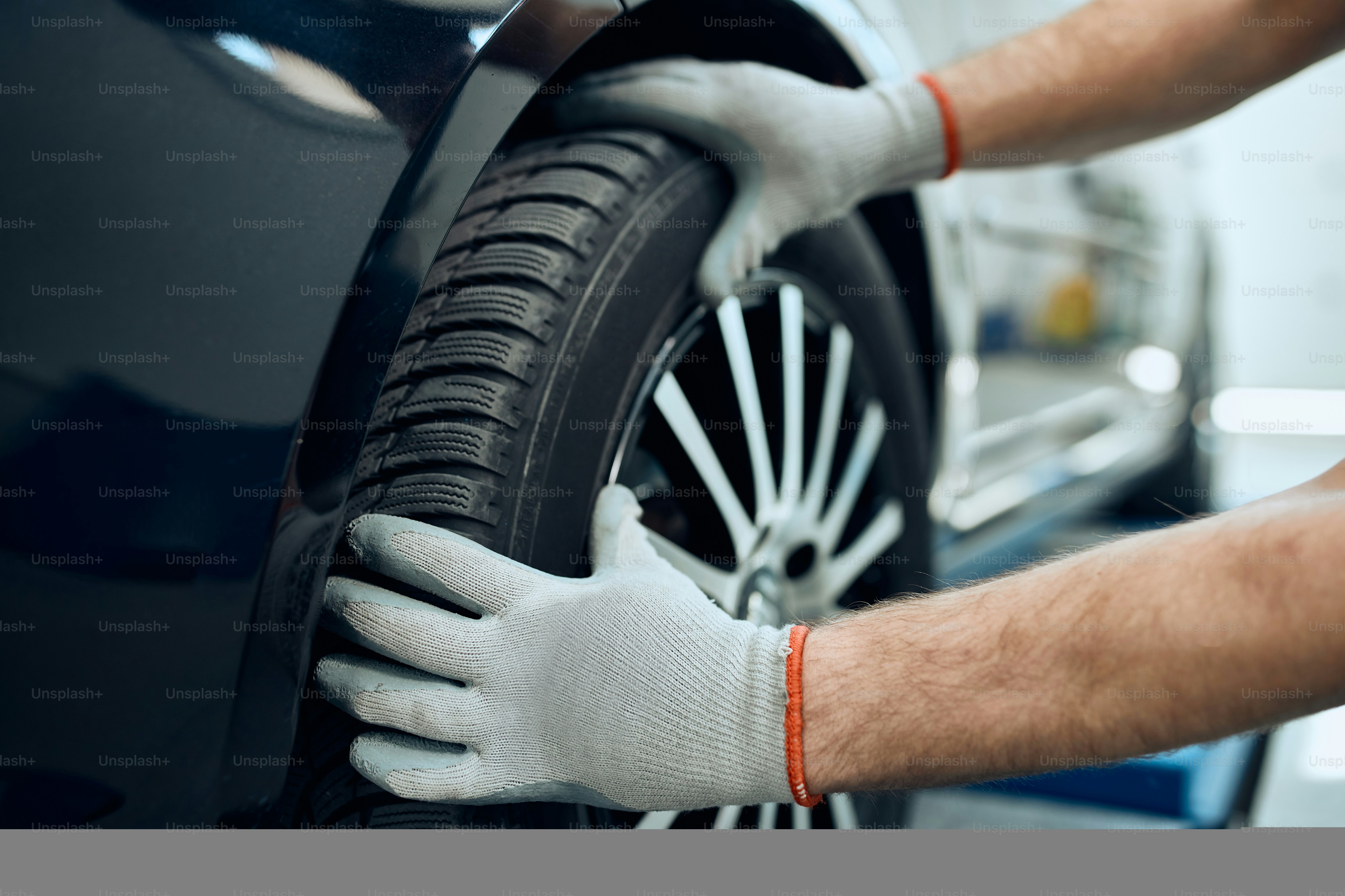 Close-up of repairman changing car tire at auto service workshop.