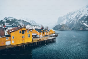 Panorama del auténtico pueblo de pescadores de Nusfjord con casas de rorbu amarillas en el fiordo noruego en invierno. Islas Lofoten, Noruega