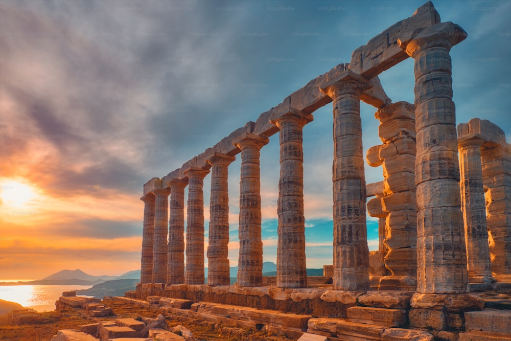 Grécia Cabo Sounio. Ruínas de um antigo templo de Poseidon, deus grego do mar, ao pôr do sol. Foto das ruínas do templo ao pôr do sol. Marco turístico da Ática, Sounion, Grécia