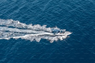Das Boot schwimmt mit hoher Geschwindigkeit auf der blauen Meerwasserfläche, Draufsicht