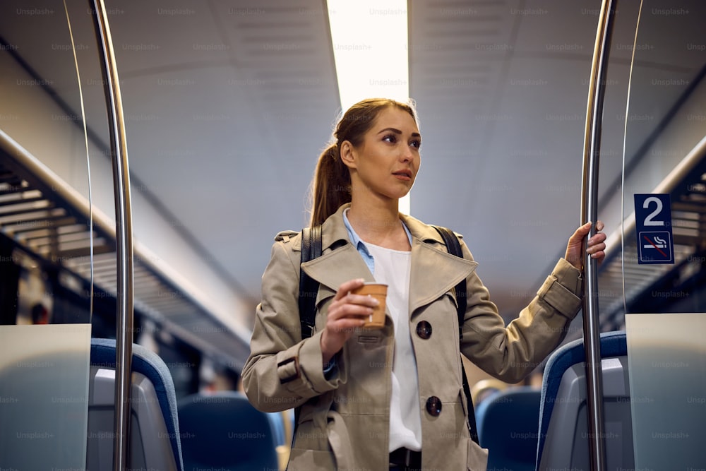 테이크아�웃 커피를 들고 기차로 통근하는 젊은 여성.