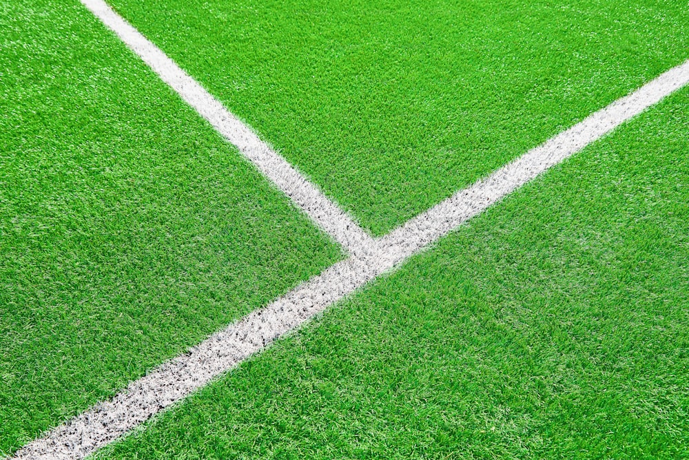 Teil des Fußballs oder Fußballplatzes aus nächster Nähe, künstliches grünes Gras mit weißen Randlinien, Kunstrasen im Stadion für Teilspiele