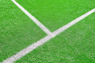 サッカーやサッカー場の一部がクローズアップされ、白い境界線を持つ人工的な緑の芝生、スパートゲーム用のスタジアムのアストロターフ