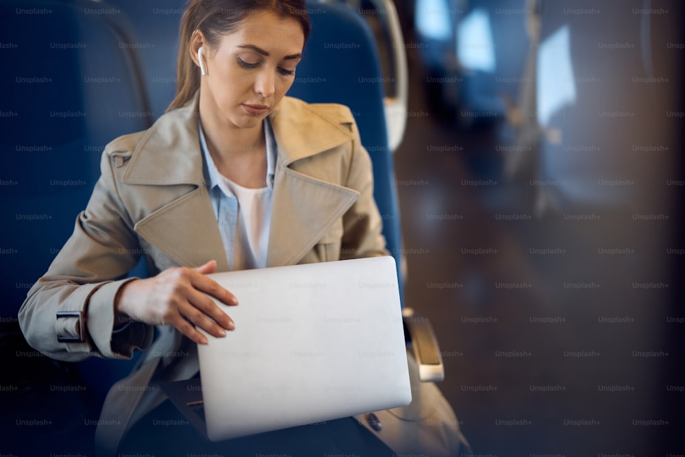 Jovem mulher usando seu computador enquanto se desloca para o trabalho de trem.