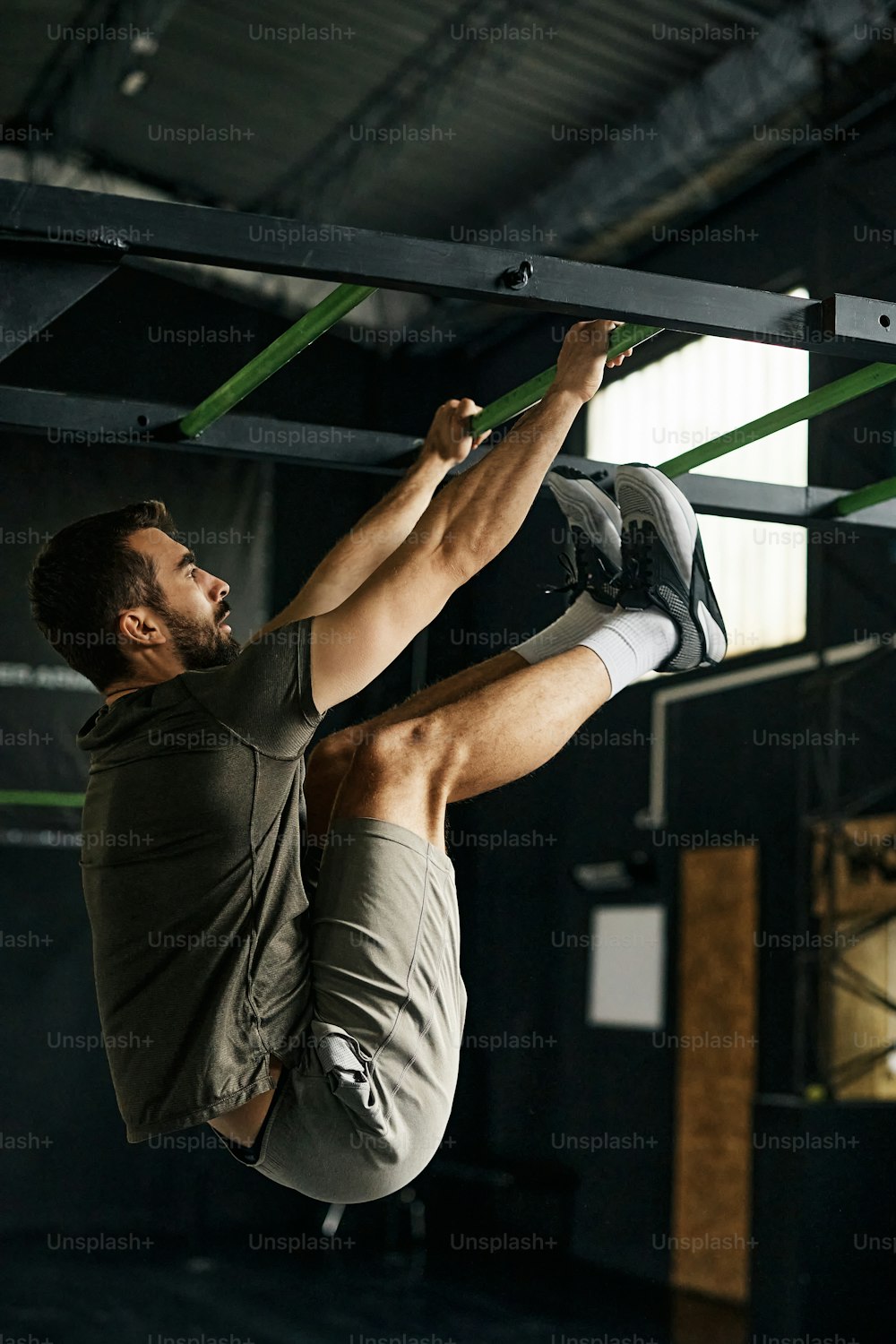 Athletic man hanging on gym ladder while during his sports training.
