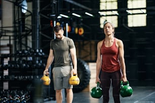 운동 여성과 그녀의 남자 친구는 체육관에서 스포츠 훈련 중에 케틀벨로 운동합니다.