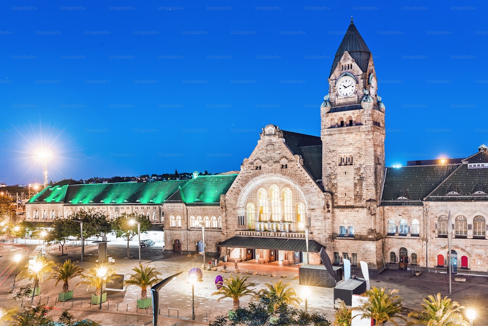 Night view of the illuminated old railway station building with clock tower in Metz city