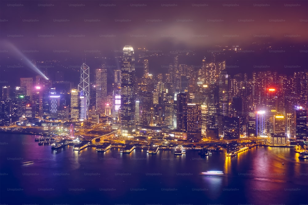 Luftaufnahme der beleuchteten Wolkenkratzer der Innenstadt von Hongkong über dem Victoria Harbour am Abend. Hongkong, China