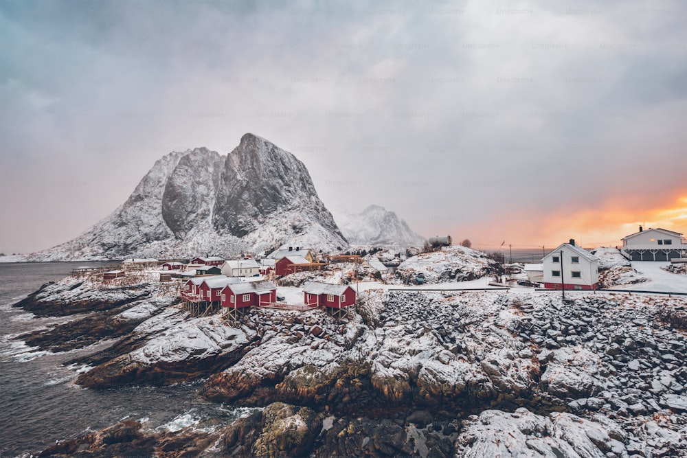 Famosa atração turística Hamnoy vila de pescadores em Lofoten Islands, Noruega com casas de rorbu vermelho. Com neve caindo no inverno ao nascer do sol