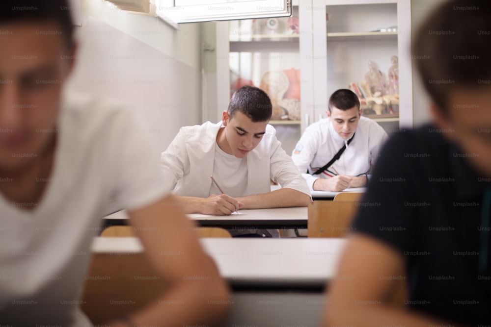 Back to school.  Teenagers students sitting in the classroom working exam.