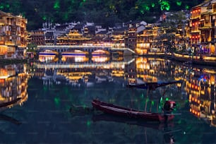 Chinese tourist attraction destination - Feng Huang Ancient Town (Phoenix Ancient Town) on Tuo Jiang River illuminated at night. Hunan Province, China