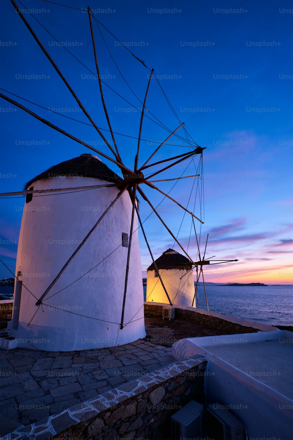 Scenic view of famous Mykonos Chora town windmills. Traditional greek windmills on Mykonos island illuminated in the evening, Cyclades, Greece. Walking with steadycam.