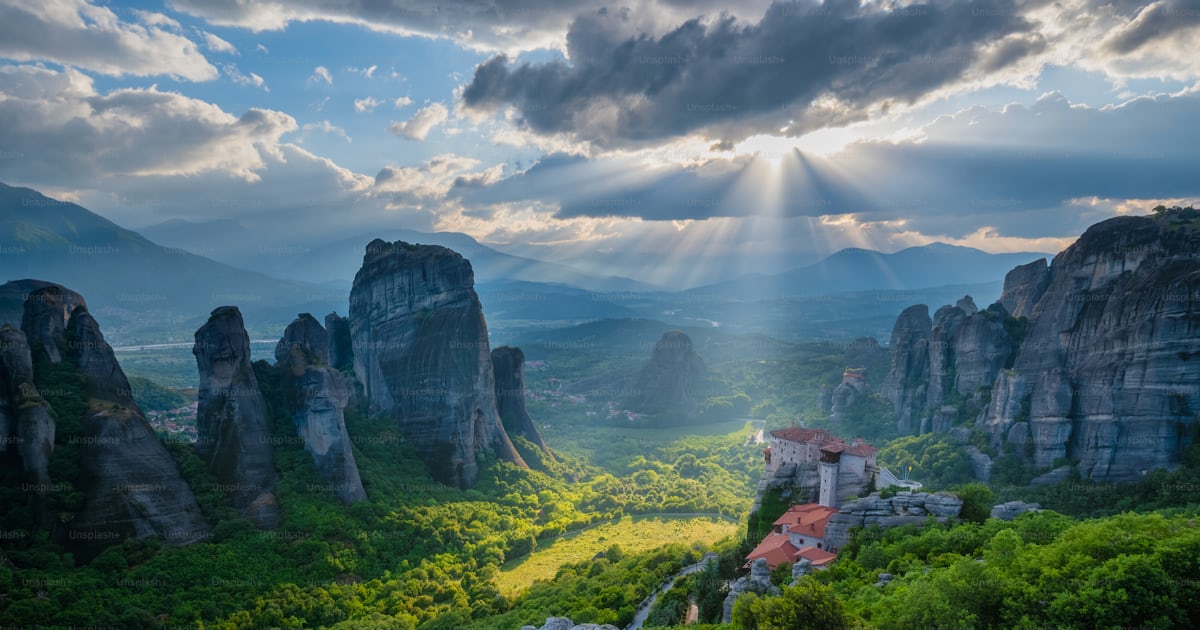 有名なギリシャの観光地ギリシャのメテオラにあるルサヌ修道院と聖ニコラス・アナパヴサ修道院に沈む夕日、太陽の光とレンズフレア、劇的な空の写真