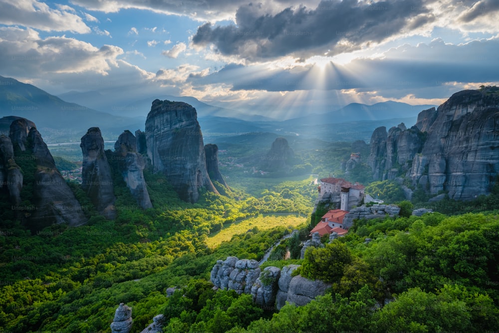 Pôr do sol sobre o mosteiro de Rousanou e Mosteiro de São Nicolau Anapavsa no famoso destino turístico grego Meteora na Grécia no pôr do sol com raios de sol e reflexo de lente e céu dramático