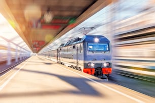 Die führende Elektrolokomotive mit Personenzug fährt mit hoher Geschwindigkeit durch den Stadtbahnsteig am Bahnhof