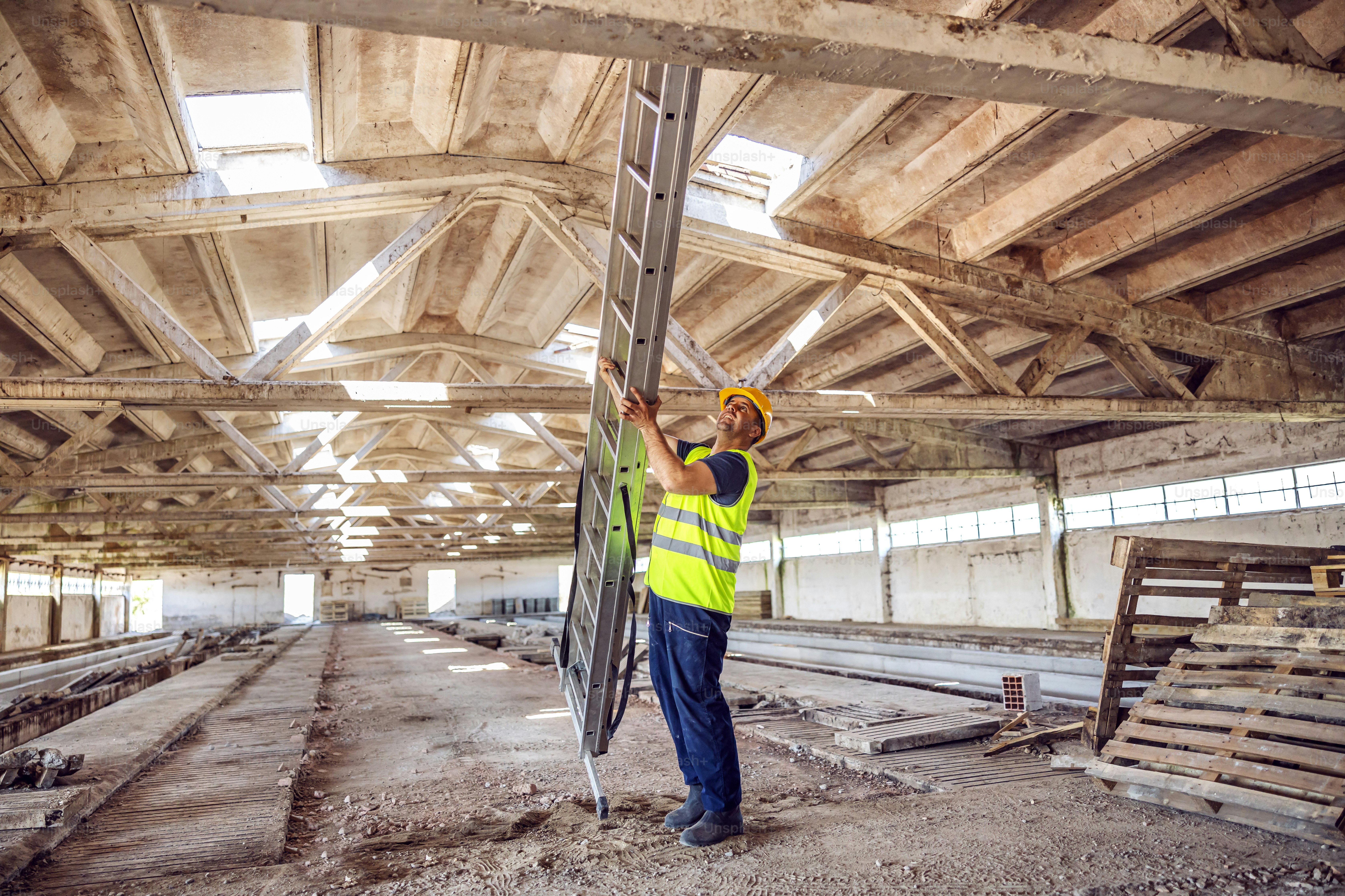 Strong worker setting ladder and preparing to climb on it.