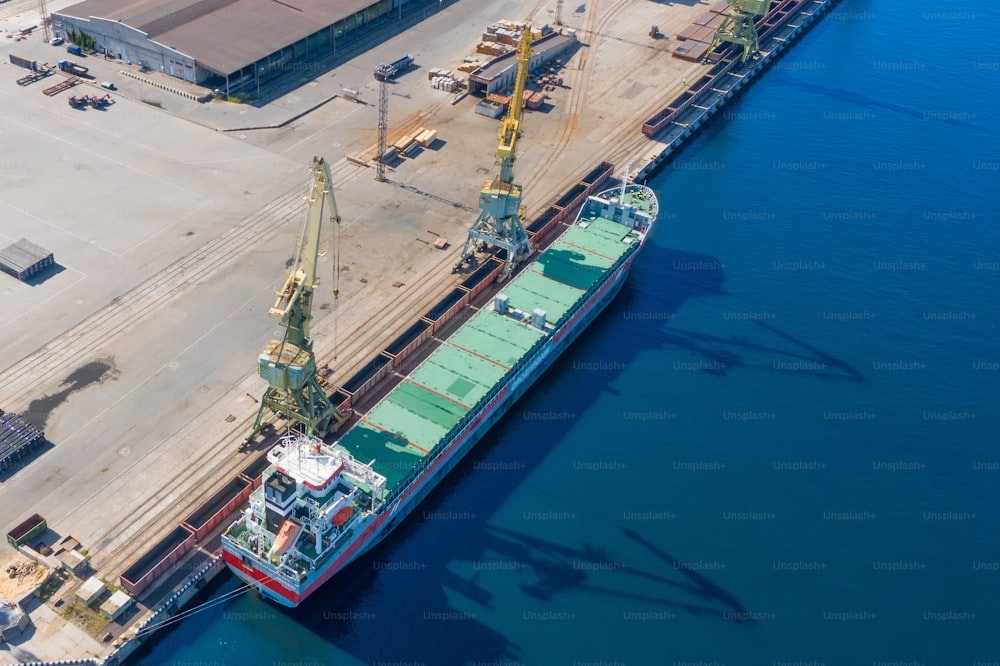 Vista aérea de la parte superior enorme buque de carga amarrado en el muelle del puerto, cargando mercancías, carga de contenedores