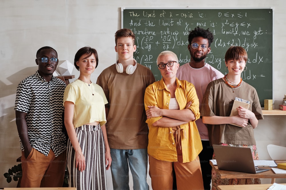 Portrait of group of students standing together with their teacher in the classroom