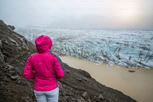 Weibliche Reisende reisen in der wunderschönen Landschaft des Svinafellsjokull-Gletschersees, Tourismusziel im Vatnajökull-Nationalpark in Island. Kalte Wintereislandschaft.