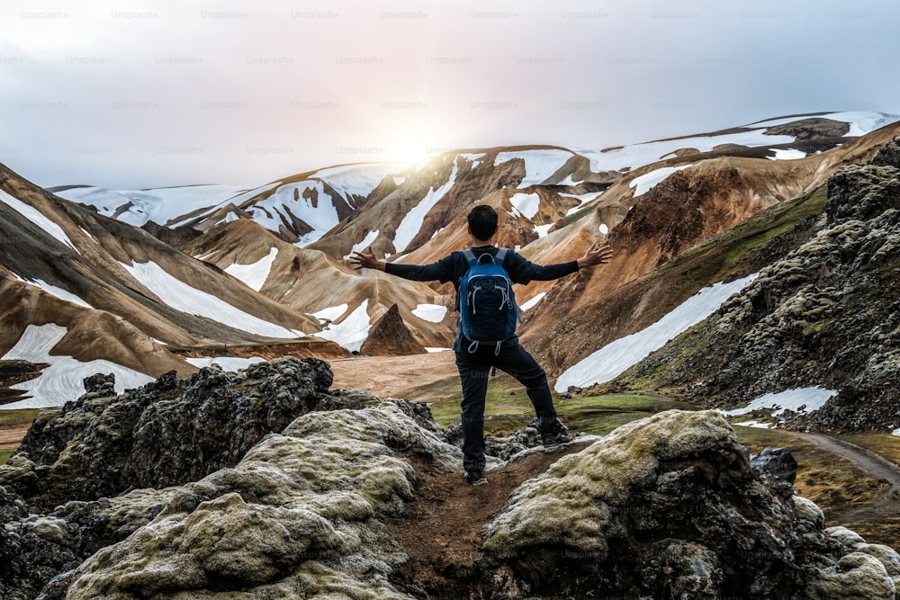 Traveler hiking at Landmannalaugar surreal nature landscape in highland of Iceland, Nordic, Europe. Beautiful colorful snow mountain terrain famous for summer trekking adventure and outdoor walking.