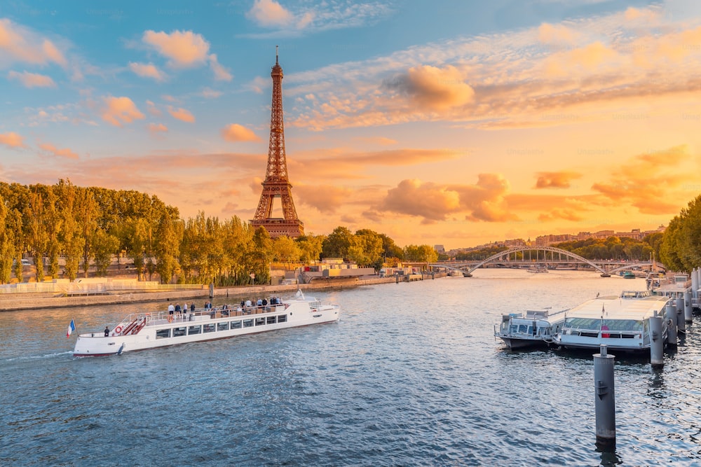 A principal atração de Paris e de toda a Europa é a Torre Eiffel nos raios do sol poente na margem do rio Sena com navios de turismo de cruzeiro