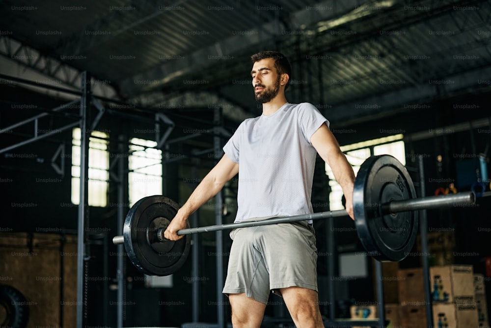 Hombre atlético que entrena con pesas mientras hace ejercicio en un gimnasio.