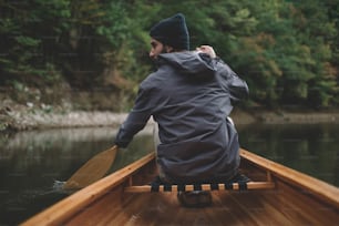 Vista traseira do homem remando canoa na floresta do lago.