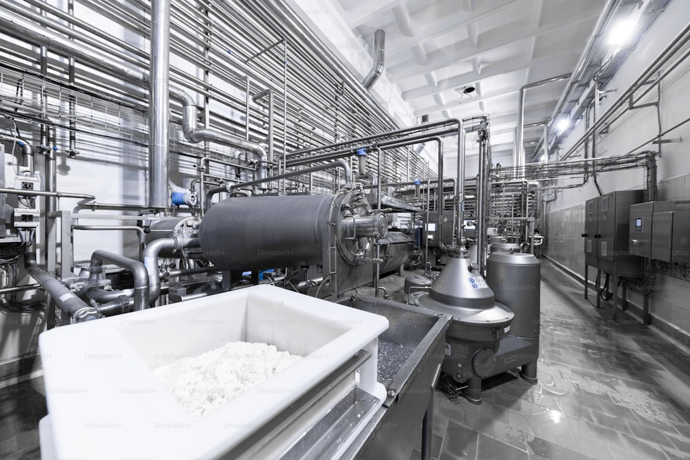 チーズや乳製品を生産する工場。パイプと金属製のはしごを備えたクロムメッキの金属タンク。工場の研修会の管路そして他の装置用具。産業界の背景。工場内部