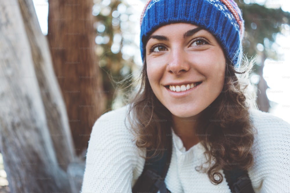 Traveling beautiful woman with backpack and knitted hat. Smiling. Laughing. Portrait.