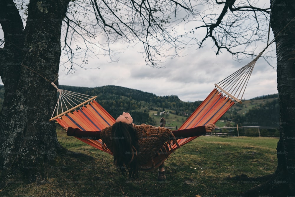 Beautiful young woman lying in hammock while relaxing on the valley under the tree