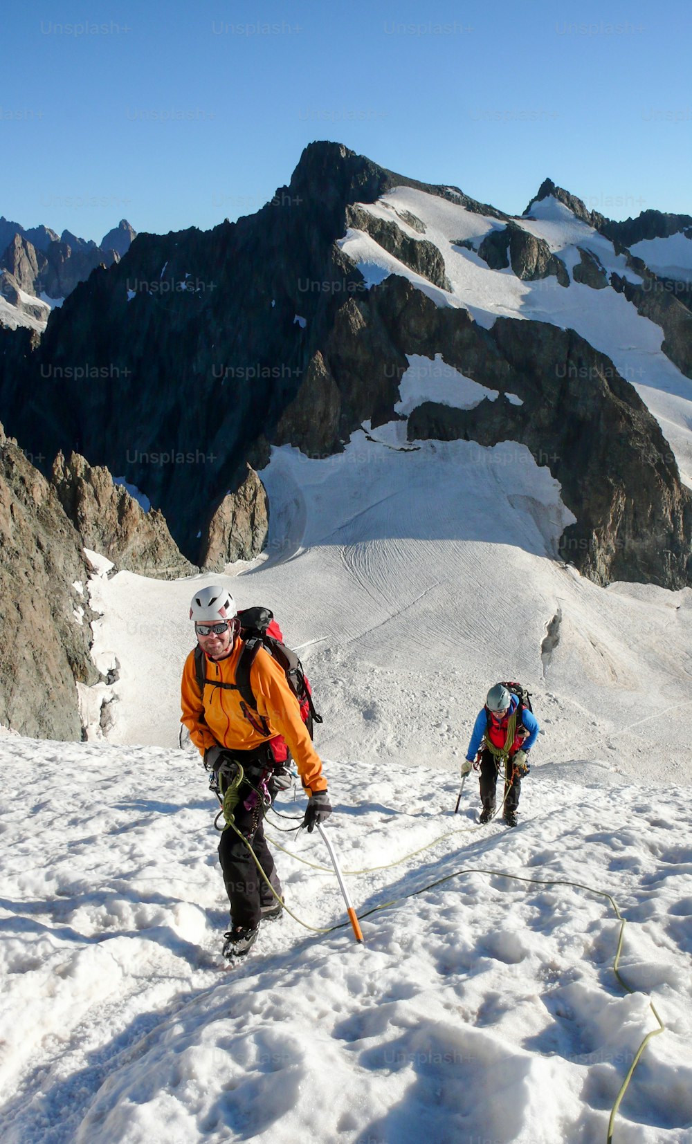 フレンチアルプスの美しい夏の朝、高いアルプスの頂上に向かって氷河を登る山岳ガイドとクライアント