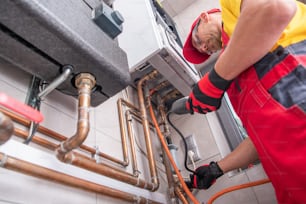 Professional Gas Heating Technician with Natural Gas Detector Device in His Hands Looking For Potential Leaks Inside the Heating Furnace System.