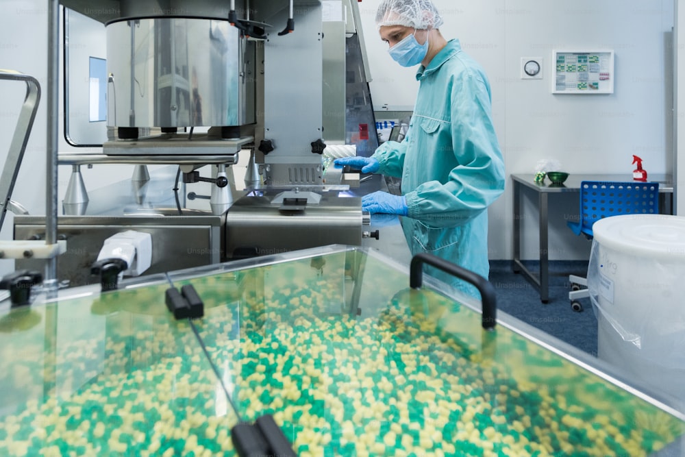 Technicien pharmaceutique en milieu stérile travaillant sur la production de pilules à l’usine de pharmacie