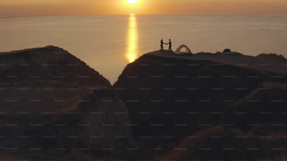 La pareja romántica de pie cerca de la tienda del camping en la orilla del mar