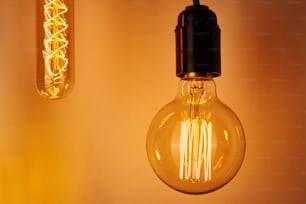 Vintage light bulb on yellow background, close up. Glowing edison bulb