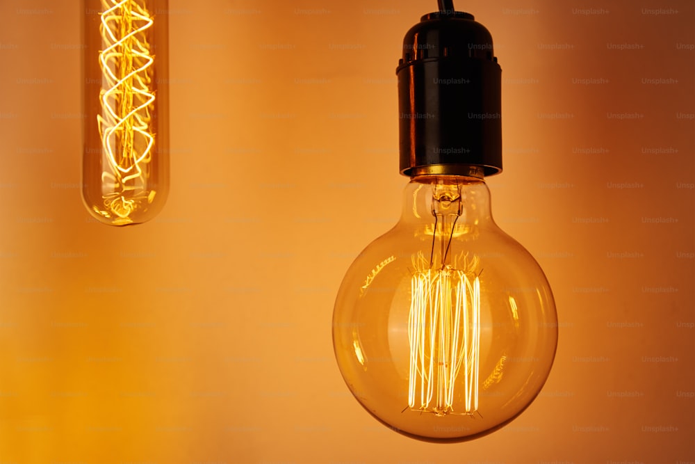 Vintage light bulb on yellow background, close up. Glowing edison bulb
