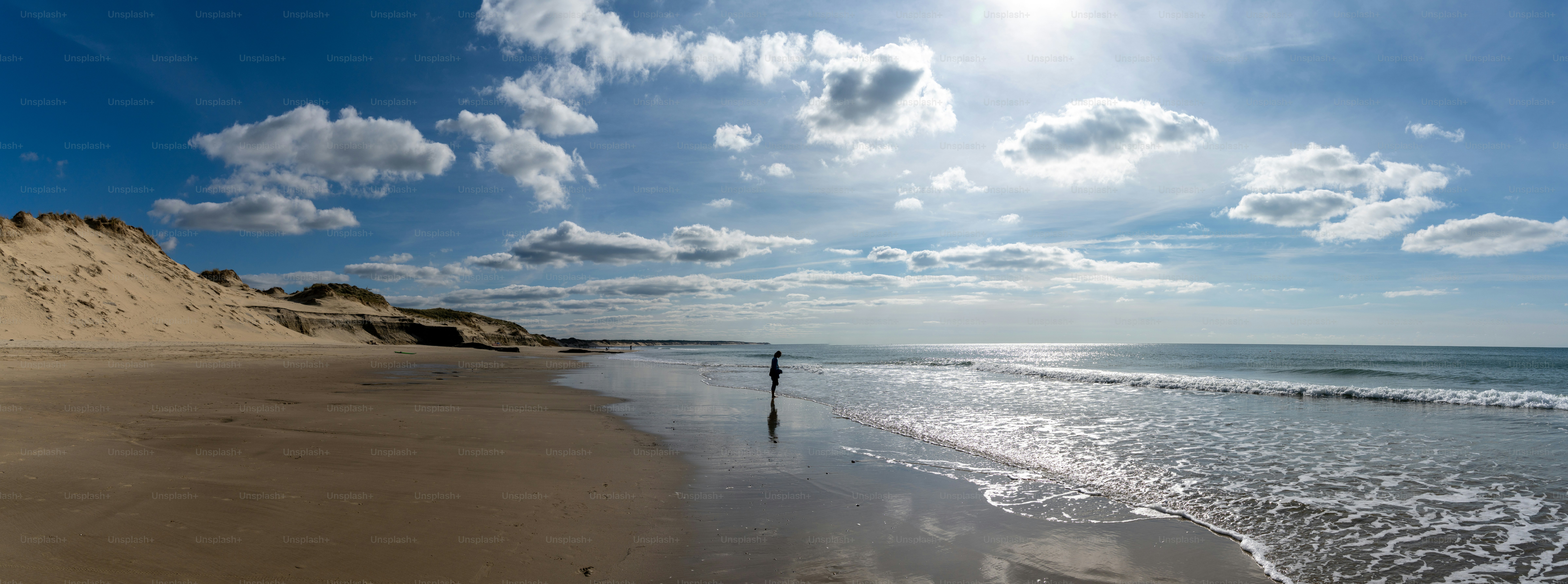 A woman in silhouette in the surf at a wild and empty beach during a beautiful sunrise