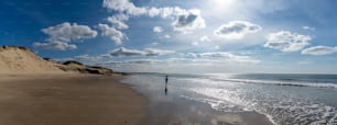 Una donna in silhouette nel surf su una spiaggia selvaggia e vuota durante una bella alba