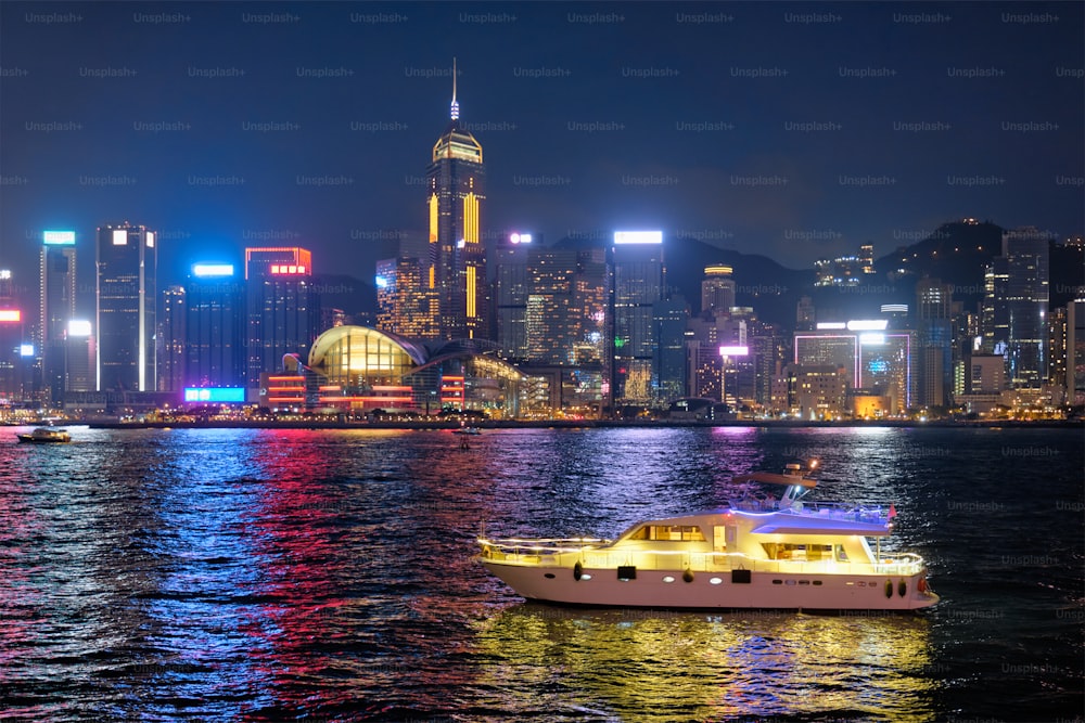 Hong Kong skyline cityscape downtown skyscrapers over Victoria Harbour in the evening illuminated with tourist boat ferries . Hong Kong, China