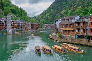 Chinese tourist attraction destination - Feng Huang Ancient Town (Phoenix Ancient Town) on Tuo Jiang River with Wanming Pagoda tower and tourist boats. Hunan Province, China