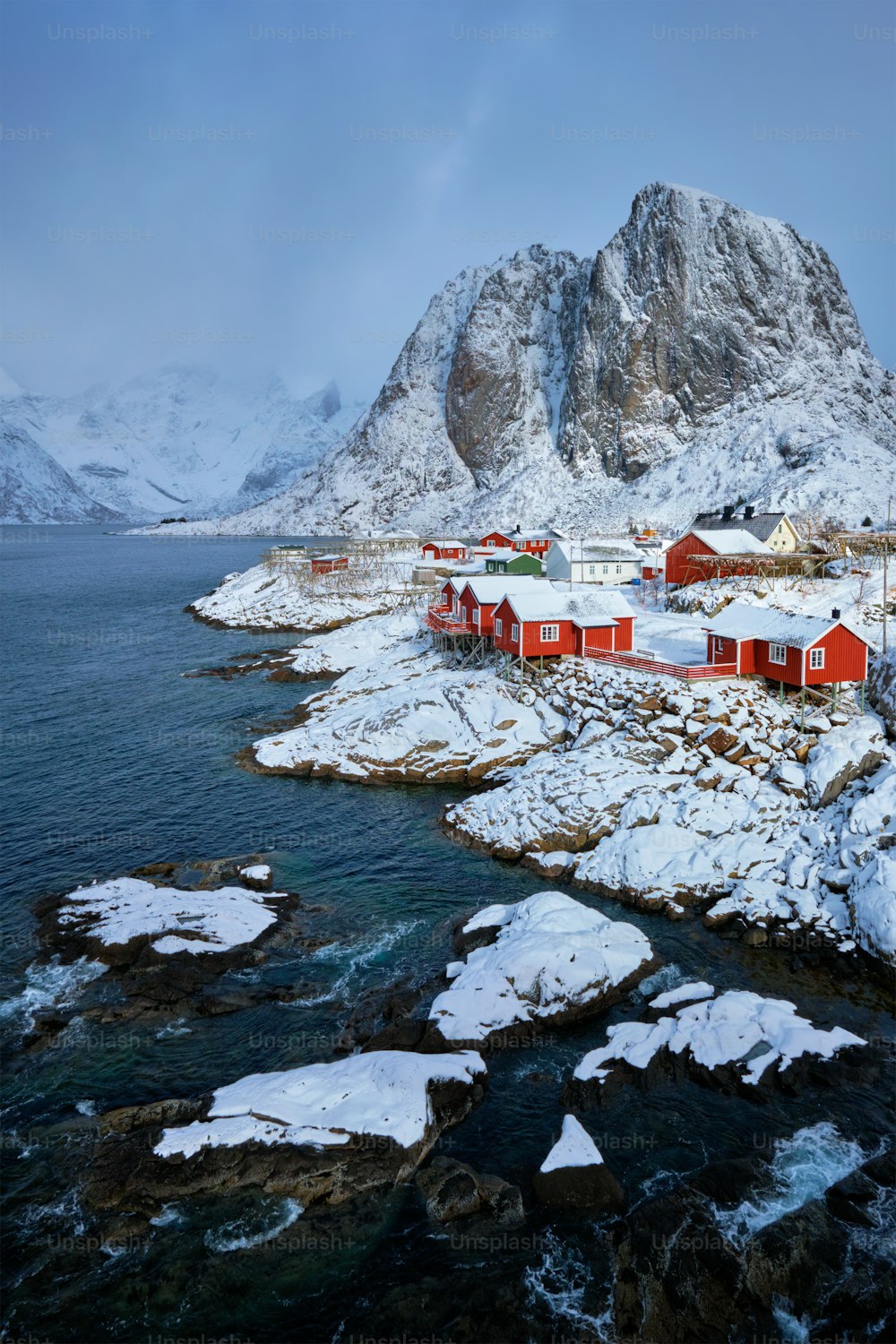 Icônica vila de pescadores de Hamnoy nas Ilhas Lofoten, Noruega, com casas de rorbu vermelho. Com neve caindo no inverno.