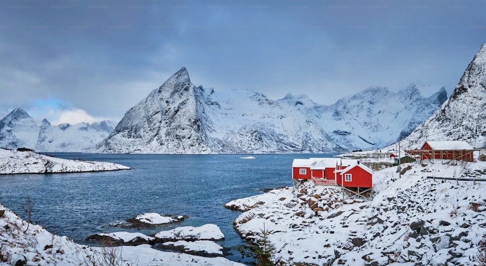 Panorama of Iconic Hamnoy fishing village on Lofoten Islands, Norway with red rorbu houses. With falling snow in winter.