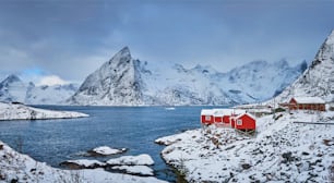 Panorama of Iconic Hamnoy fishing village on Lofoten Islands, Norway with red rorbu houses. With falling snow in winter.