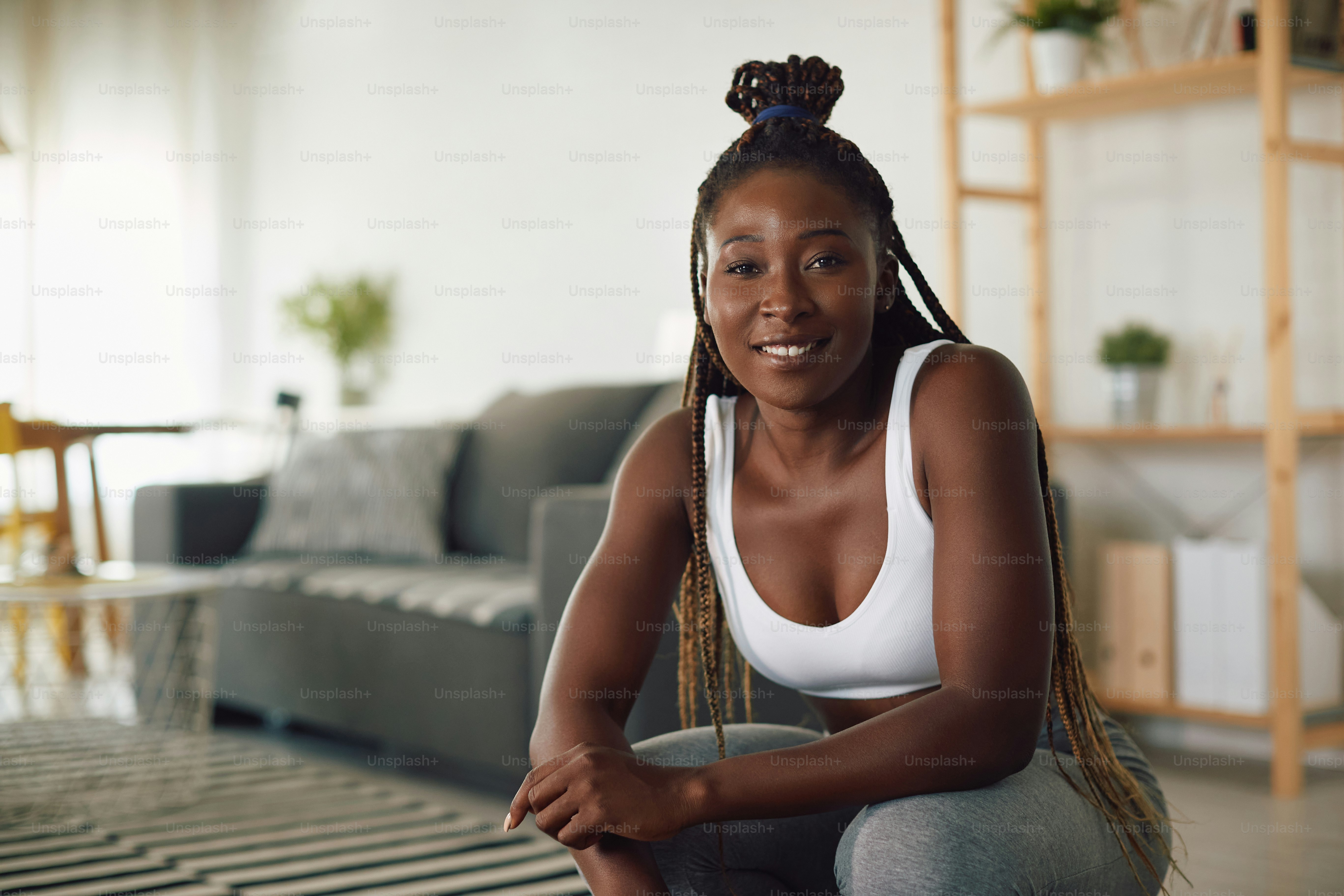 Young happy African American sportswoman working out at home and looking at camera.